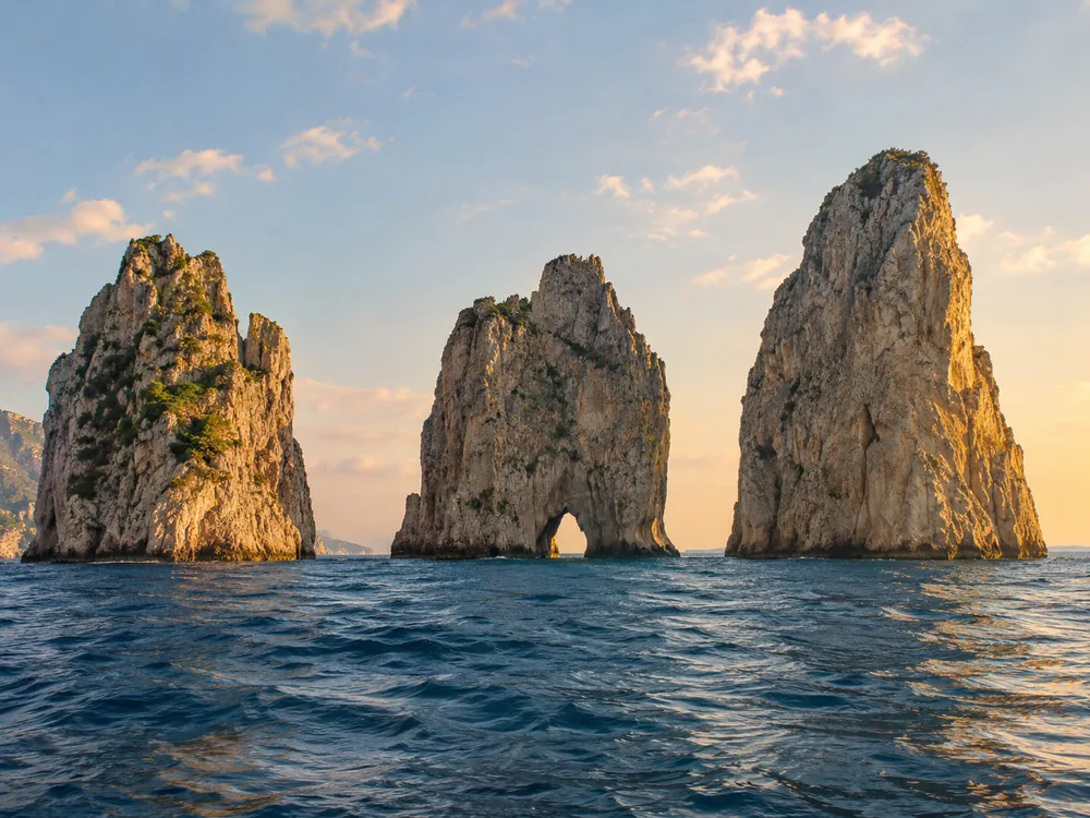Barche da escursione lungo la costa di Capri, vicino ai Faraglioni